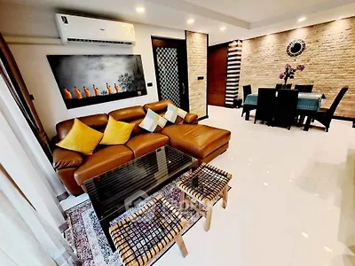 Stylish living room with leather sofa, modern decor, and dining area in open layout apartment.