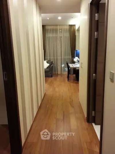 Stylish apartment hallway leading to cozy living room with wooden flooring.
