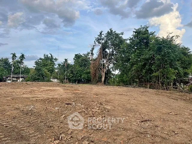 Spacious cleared land plot ready for development with lush greenery backdrop.