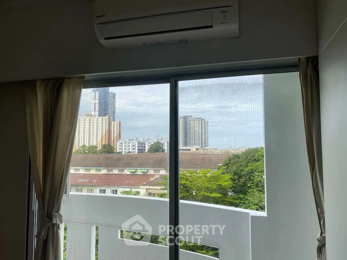 Modern apartment window view with cityscape and greenery