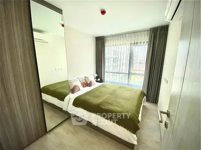 Modern bedroom with large window and mirrored wardrobe in a stylish apartment.