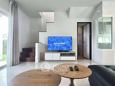 Modern living room with sleek furniture and TV under staircase, showcasing open layout and natural light.