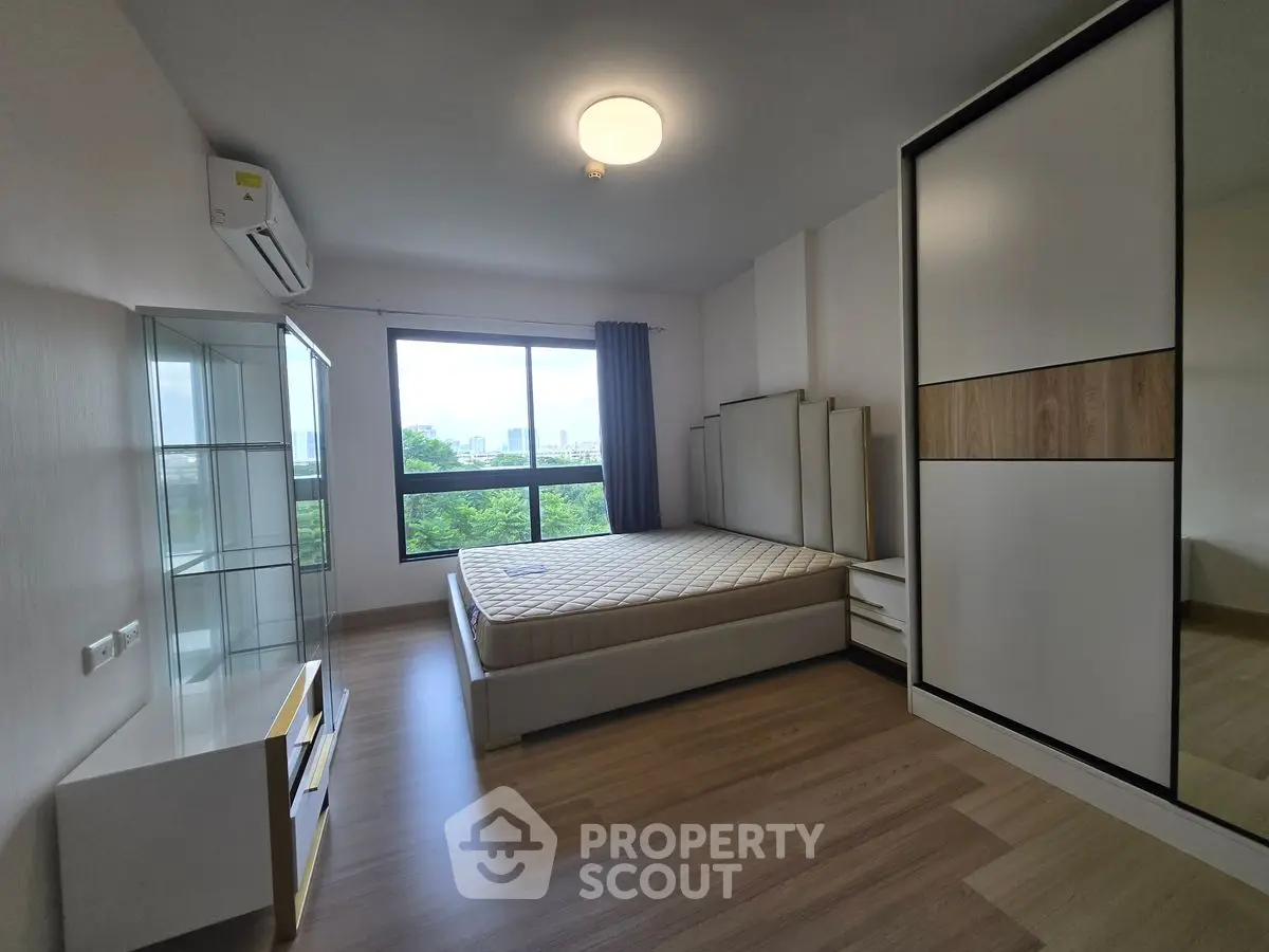 Spacious bedroom with modern furnishings and large window offering scenic views.