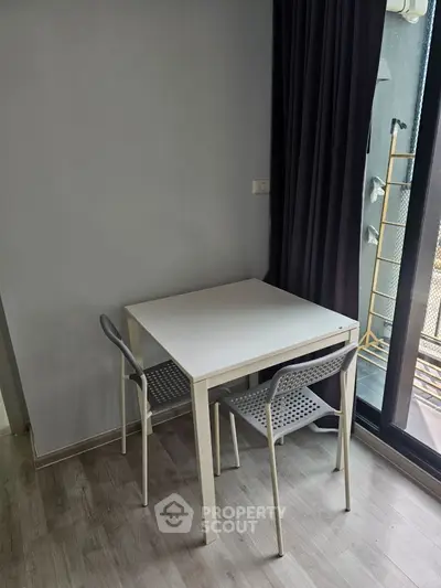 Minimalist dining area with modern table and chairs near a balcony, perfect for cozy meals.