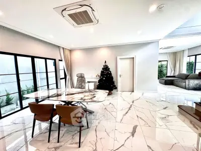 Luxurious open-plan living room with marble flooring and modern furniture, featuring a Christmas tree.