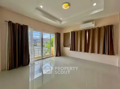 Spacious living room with large windows and balcony access, featuring modern ceiling lights and air conditioning.