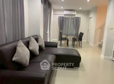 Modern living room with sleek leather sofa and dining area, featuring elegant curtains and ambient lighting.