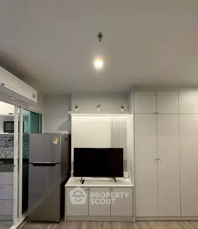 Modern living room with sleek storage, TV unit, and adjacent kitchen view.