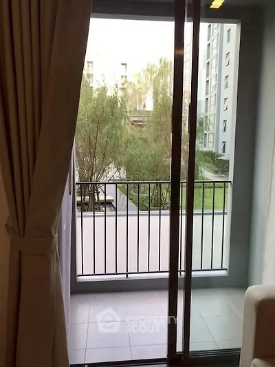 Cozy apartment balcony with serene garden view and sliding glass doors.