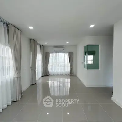 Spacious and bright living room with large windows and modern tile flooring.