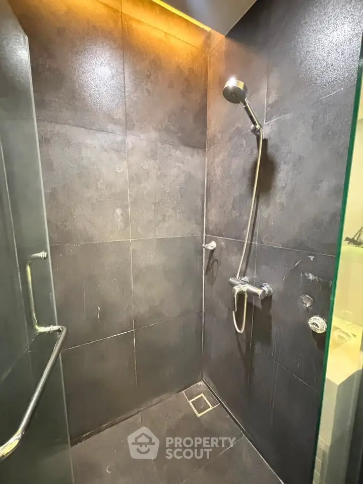 Modern bathroom shower with sleek dark tiles and contemporary fixtures