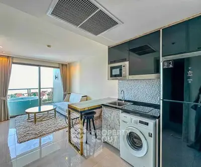 Modern open-plan living room with kitchen, featuring washing machine and balcony view.