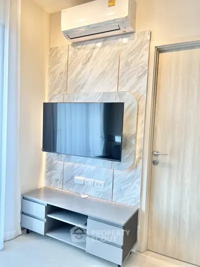 Modern living room with mounted TV and sleek air conditioning unit, featuring elegant marble wall design.