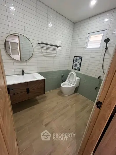 Modern bathroom with sleek design, featuring a round mirror, stylish vanity, and contemporary fixtures.