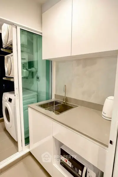 Modern kitchen with sleek cabinetry and integrated laundry appliances.