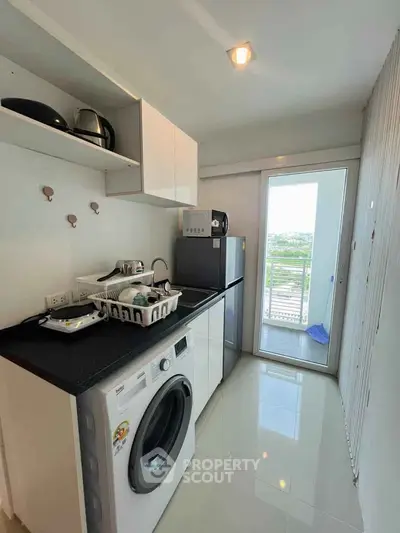 Modern kitchen with washing machine and balcony view in sleek apartment.