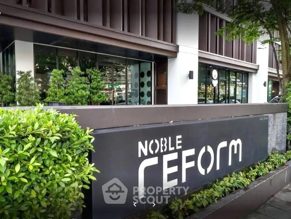 Modern building exterior with lush greenery and stylish signage at Noble Reform.