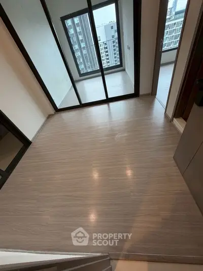 Modern apartment with sleek flooring and large windows offering city views.