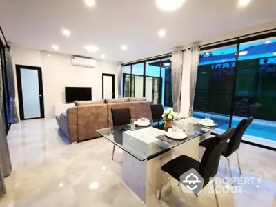 Spacious and modern living area seamlessly connected to an elegant dining space, featuring glossy marble floors and large windows with a view of the pool.