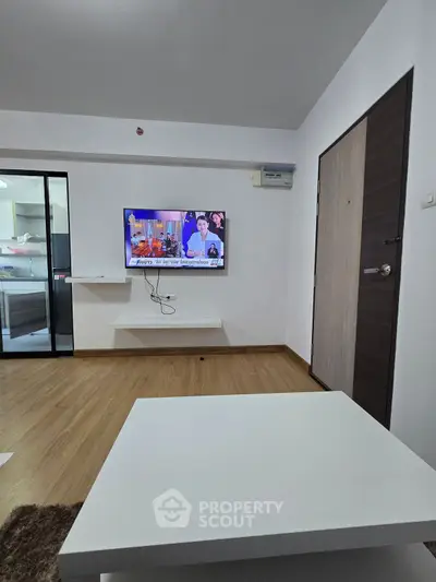 Modern living room with wall-mounted TV and sleek wooden flooring