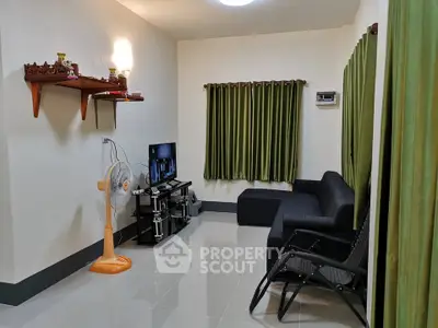Cozy living room with modern decor and green curtains, featuring a TV and comfortable seating.