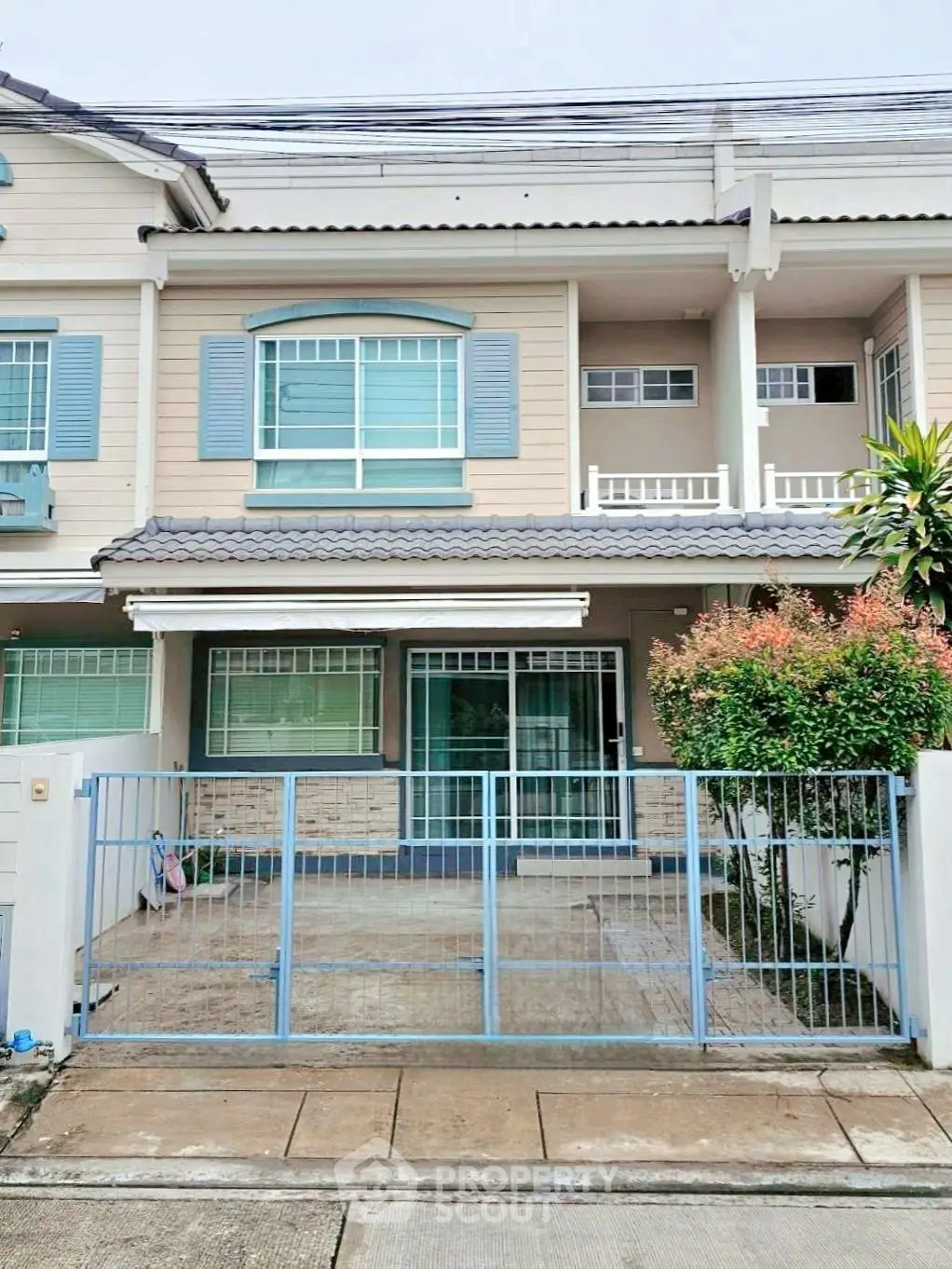 Charming townhouse with blue accents and gated front yard in a serene neighborhood.