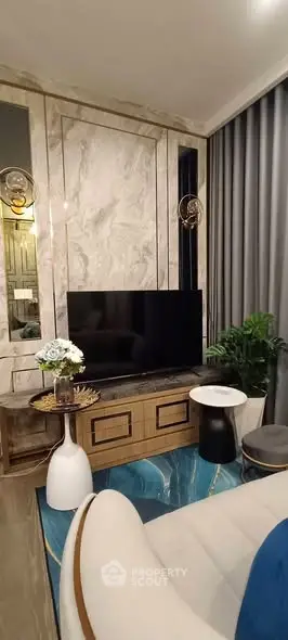 Luxurious living room with modern decor, marble accents, and large flat-screen TV.