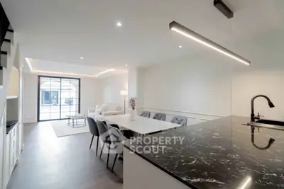 Modern open-plan living and dining area with sleek black marble countertop and stylish lighting.
