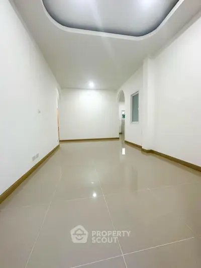 Spacious empty room with glossy tiled floor and elegant ceiling design