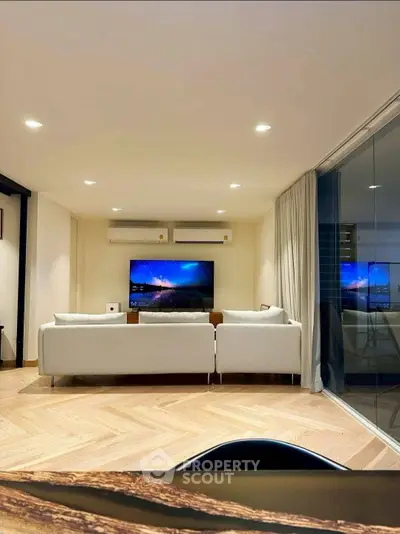 Modern living room with sleek design, large TV, and cozy seating area, perfect for relaxation.