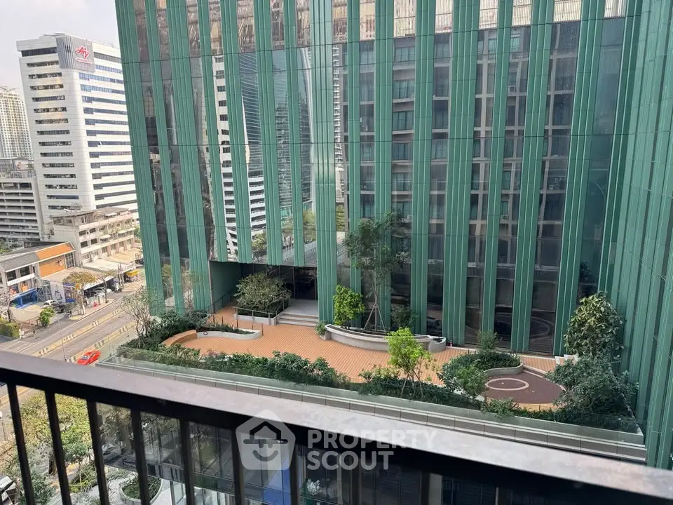 Stunning urban view from a high-rise balcony overlooking modern architecture and lush greenery.