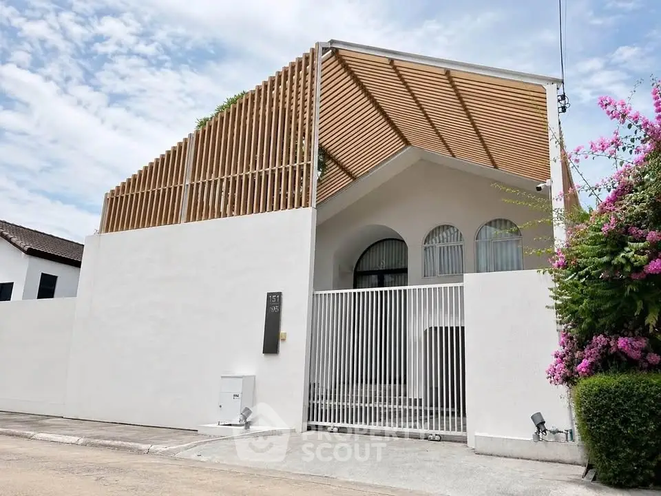 Modern architectural home with stylish wooden slats and lush greenery, offering privacy and elegance in a serene neighborhood.