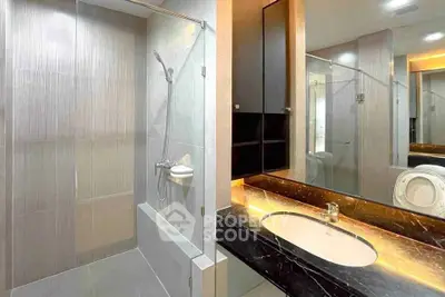 Modern bathroom with sleek design, featuring a glass shower and elegant vanity.