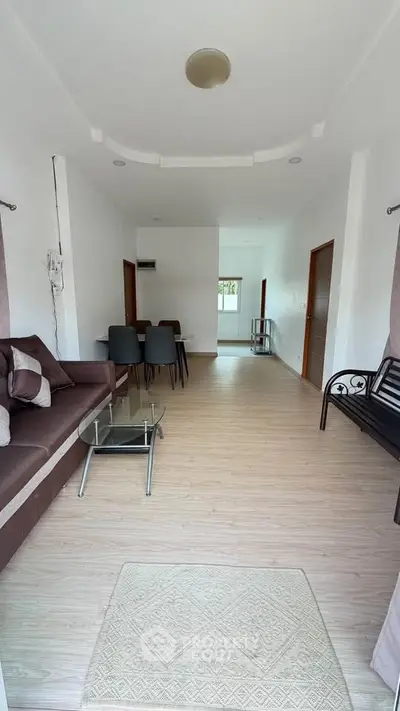 Spacious living room with modern furniture and dining area in open layout apartment.