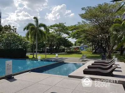 Luxurious outdoor pool area with lush greenery and modern sun loungers, perfect for relaxation.