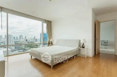 Spacious bedroom with stunning city view and modern furnishings in a high-rise apartment.