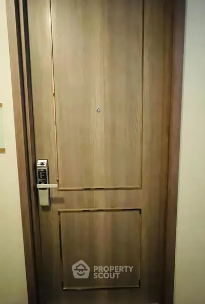 Elegant wooden door with modern electronic lock in upscale apartment building.