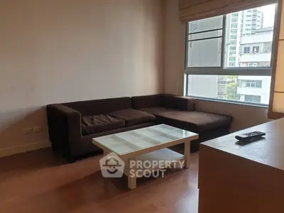 Cozy living room with brown sectional sofa and glass coffee table, featuring large window with city view.