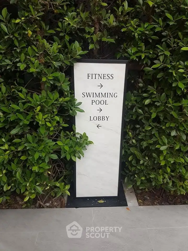 Elegant directional sign in lush garden setting for fitness, pool, and lobby access.