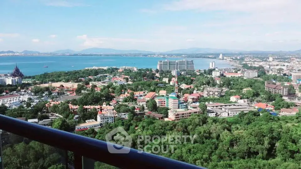 Stunning panoramic view from high-rise balcony overlooking cityscape and ocean.