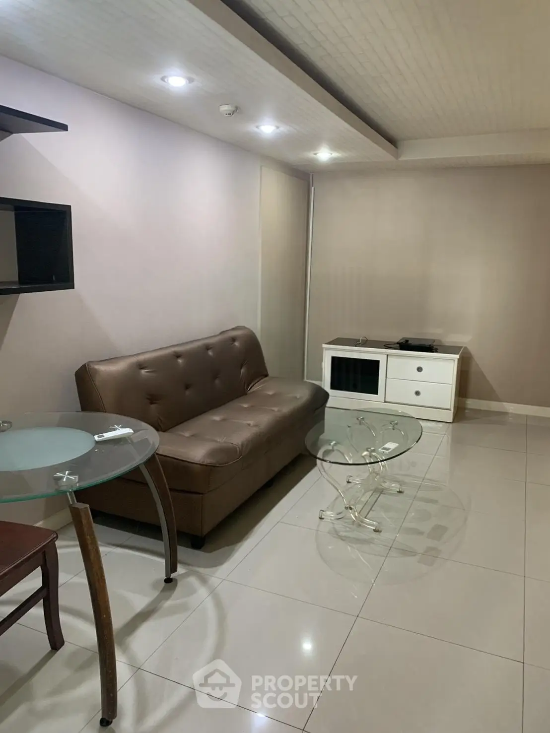 Modern living room with sleek furniture and glass tables in a cozy apartment setting.