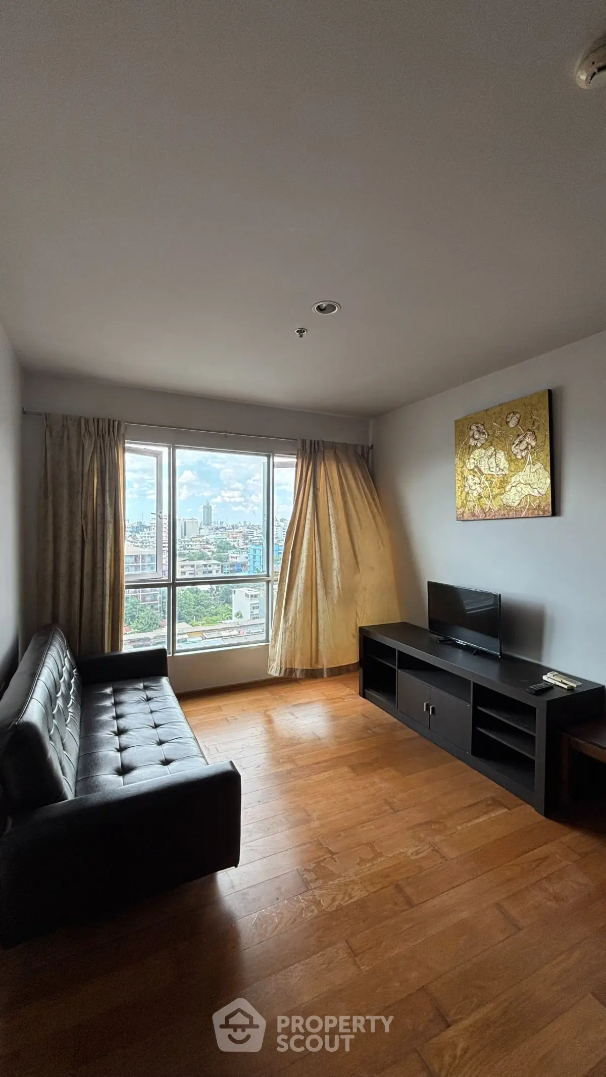 Spacious living room with city view, featuring a modern sofa and entertainment unit, perfect for urban living.