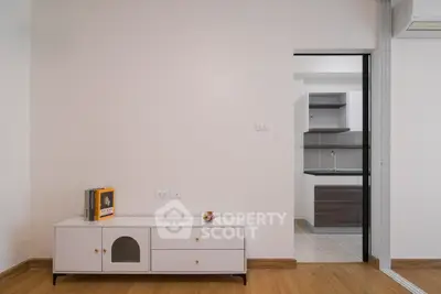 Modern minimalist living room with sleek cabinetry and open kitchen view.