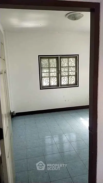 Spacious empty room with tiled floor and window, perfect for customization.