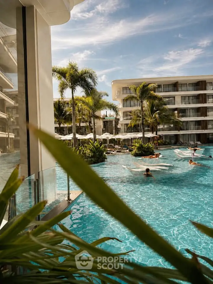 Luxurious resort-style pool with palm trees and modern apartment buildings under a clear blue sky.