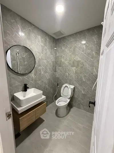 Modern bathroom with sleek design, featuring a round mirror, stylish sink, and elegant tile work.