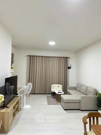 Modern living room with stylish furniture and neutral tones, featuring a cozy sofa and entertainment center.