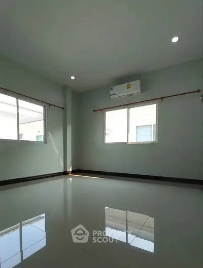 Spacious empty room with glossy tiled floor and large windows, perfect for customization.