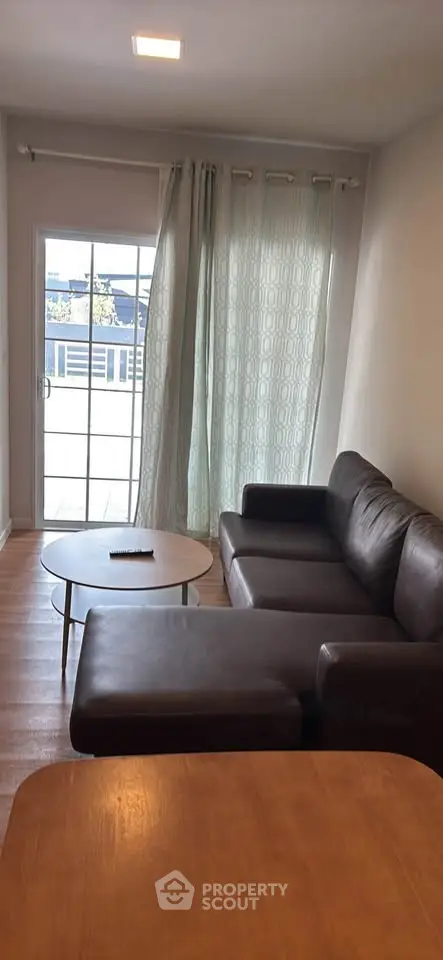 Cozy living room with modern leather sofa and natural light from large window.