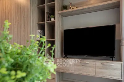 Modern living room with sleek wooden shelves and large flat-screen TV, perfect for entertainment.